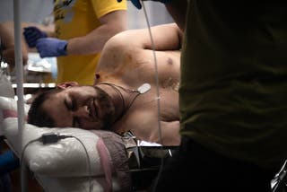 A soldier injured by drone shrapnel closes his eyes during treatment